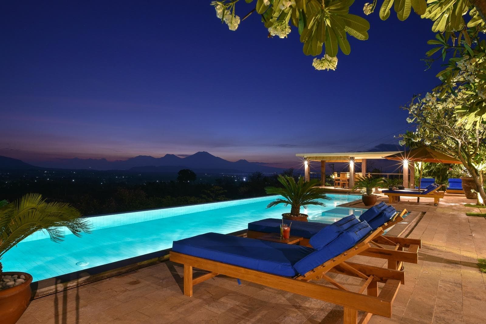 A stunning infinity pool at a Bali villa overlooking the ocean at sunset.